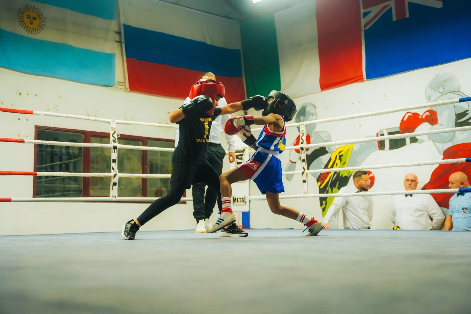 Boxe éducative à Blagnac, de 7 à 12 ans : deux enfants casqués échangent en touche légère sous le regard des juges